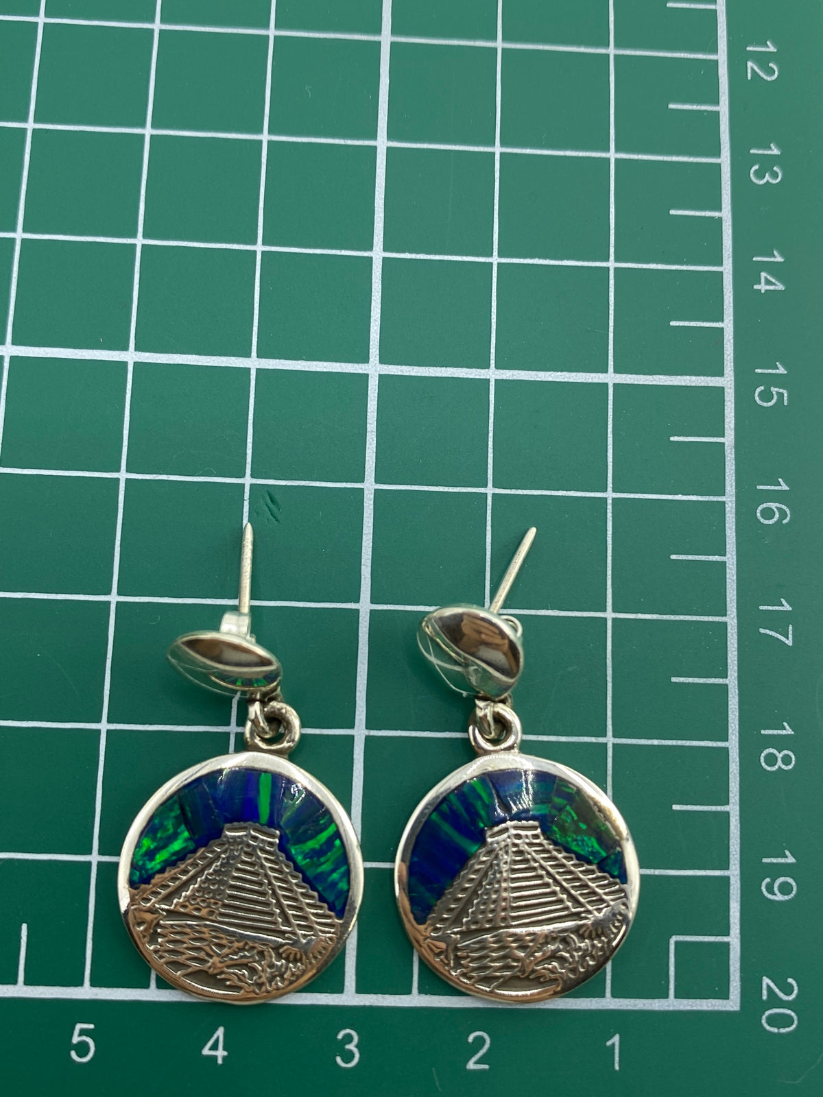 Aretes en la mano mostrando el Quinto de autenticidad en la parte trasera
