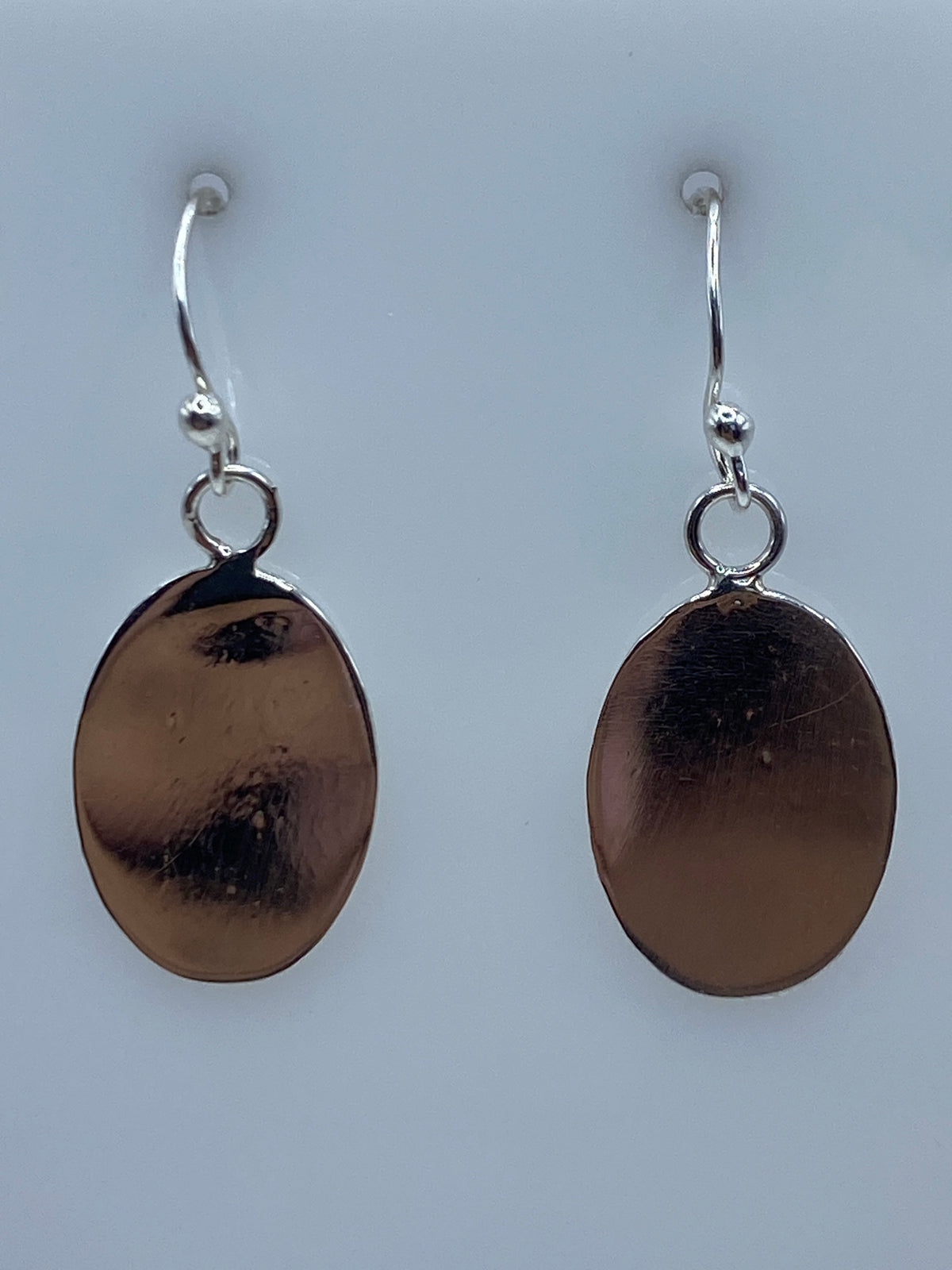 Detalle de los aretes de plata mostrando la textura grabada en la superficie