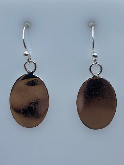 Detalle de los aretes de plata mostrando la textura grabada en la superficie