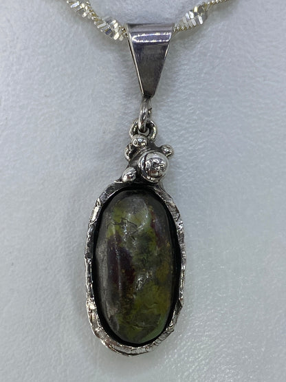 Detalle cercano del engaste de la piedra verde en plata 925 de Taxco
