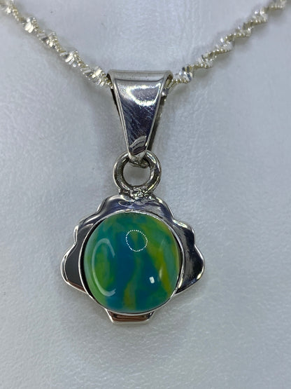 Dije de plata 925 con piedra multicolor de 3 cm de largo, colgado de cadena en la mano