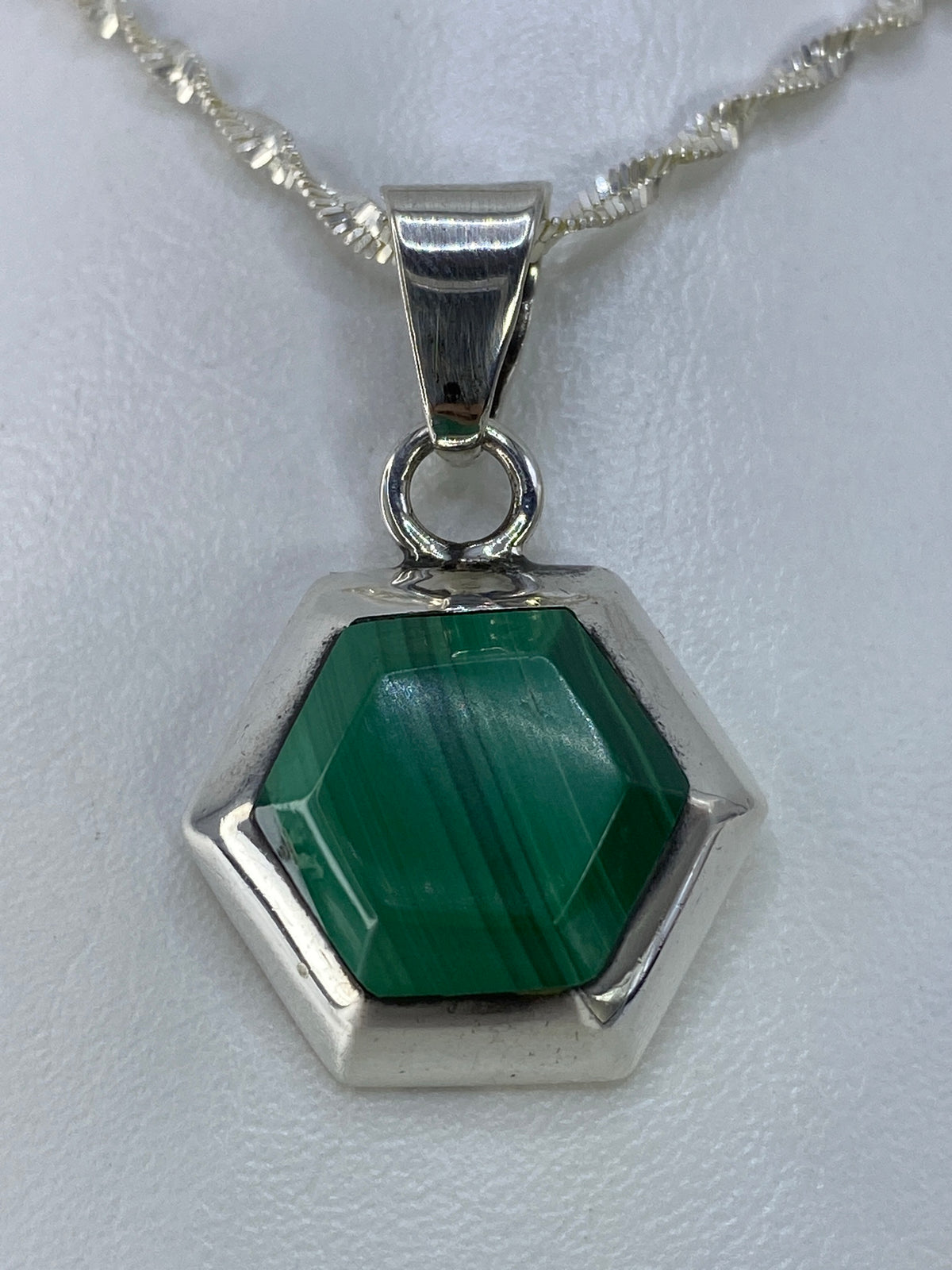 Detalle del dije desde arriba mostrando la piedra verde y el engaste de plata