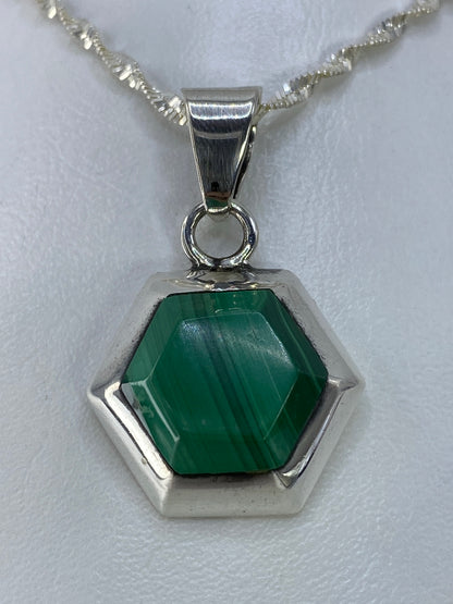 Detalle del dije desde arriba mostrando la piedra verde y el engaste de plata