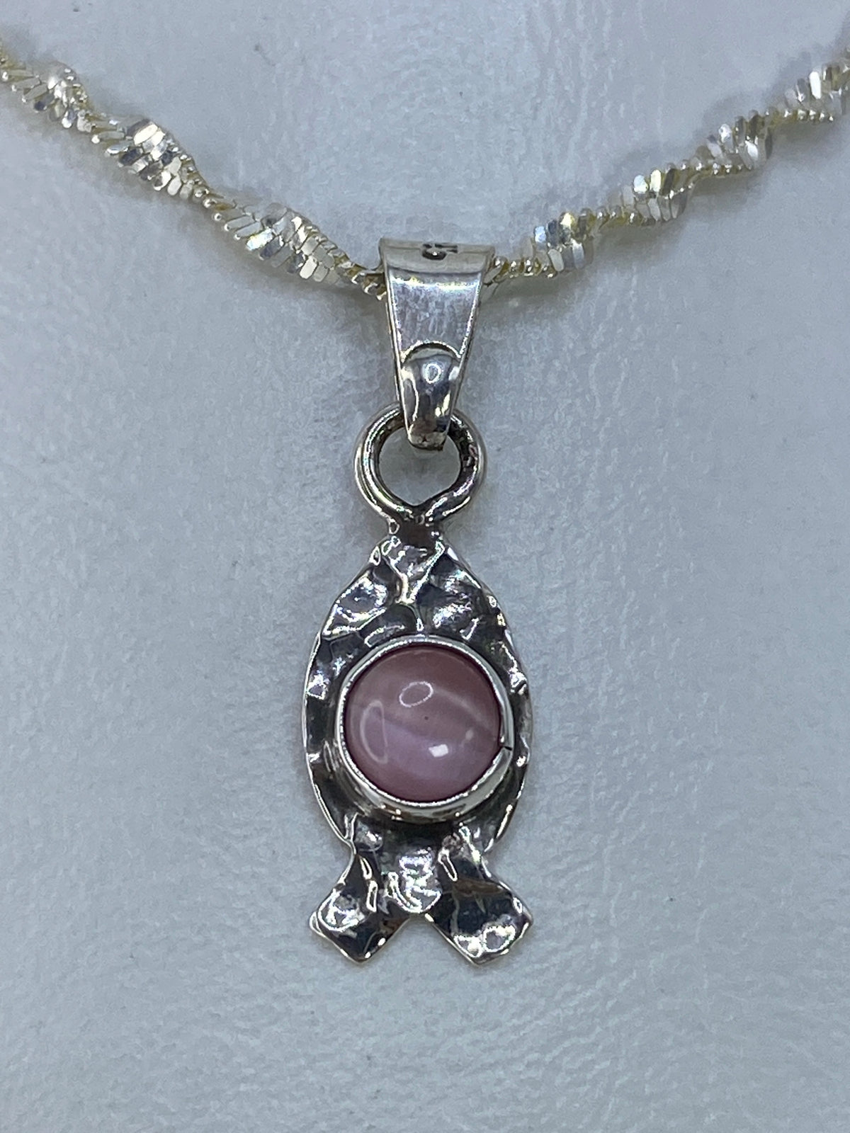 Dije de plata con engaste texturado y piedra rosa, vista lateral
