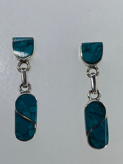 Par de aretes de plata 950 con turquesa azul engastada, colgando de una barra.