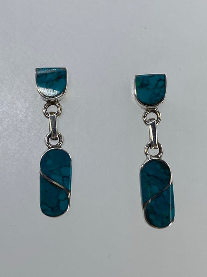Detalle lateral de los aretes mostrando la incrustación de turquesa y el engaste de plata pulida.