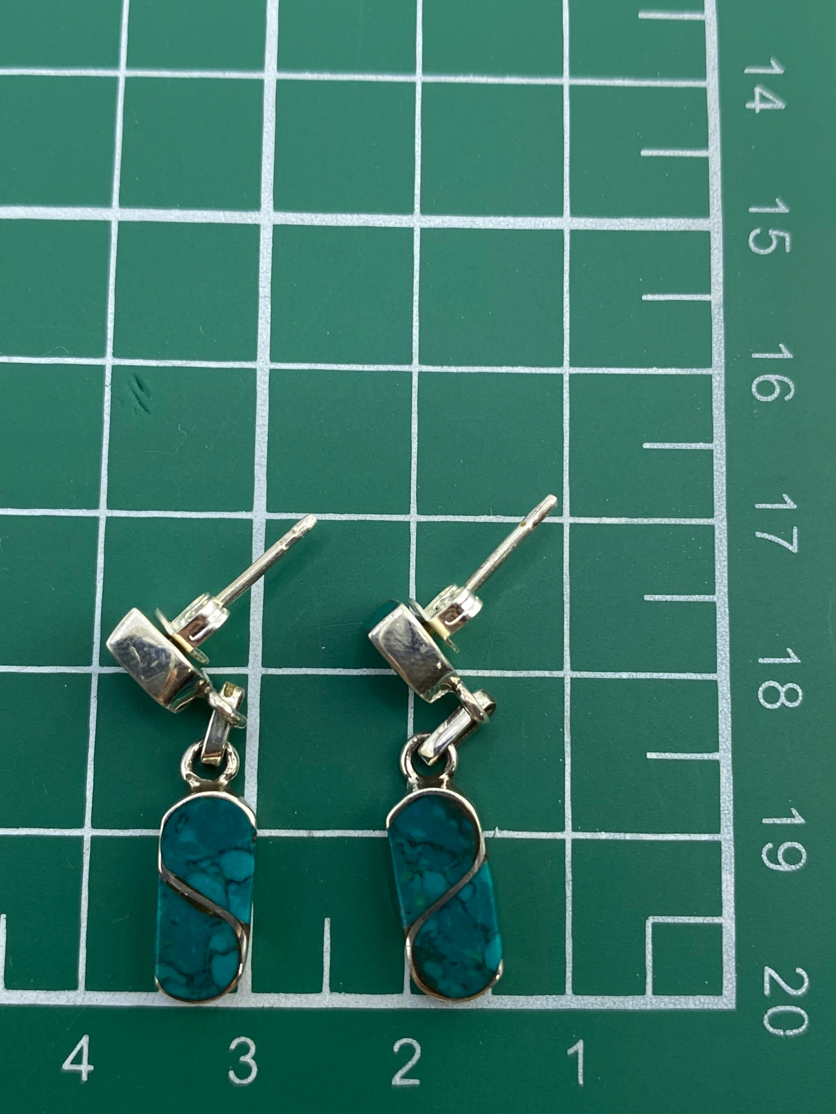 Aretes en plata 950 con marca de autenticidad, sobre fondo blanco.