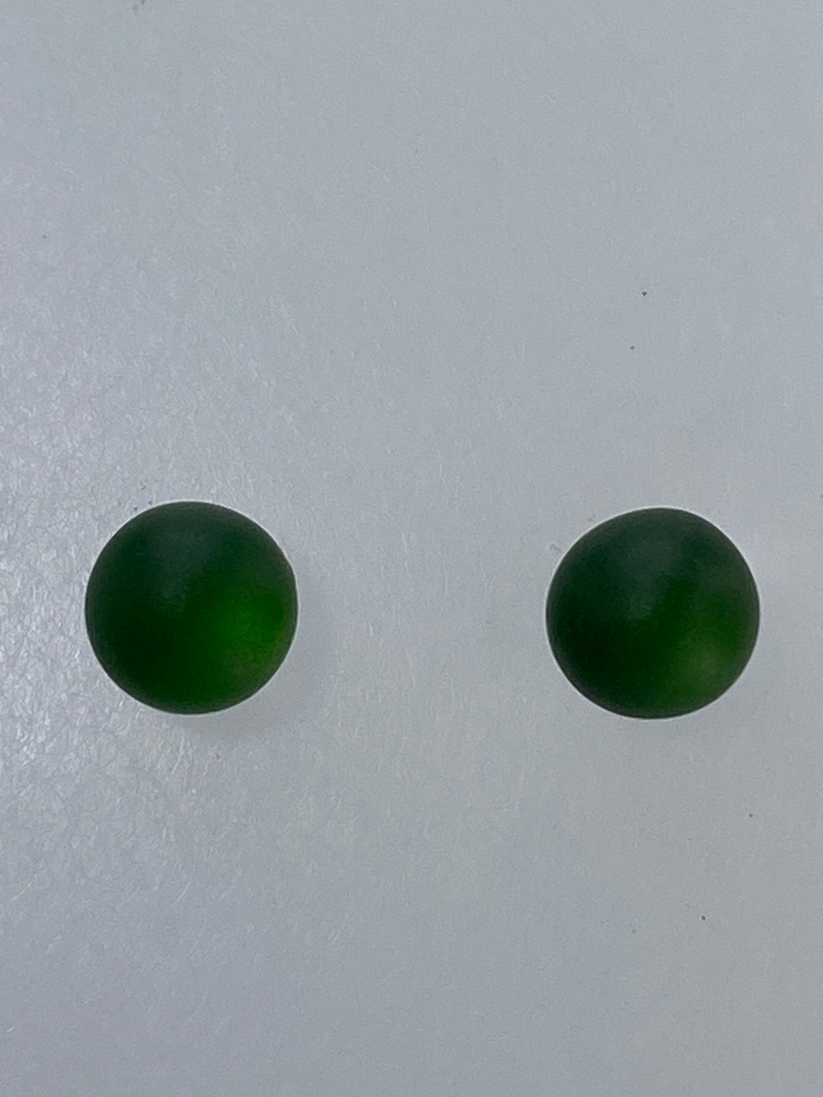 Par de aretes de plata 925 con piedra verde redondeada, sobre fondo blanco
