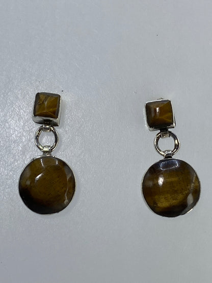Aretes de plata con Ojo de Gato café colgando en par, con destellos naturales visibles