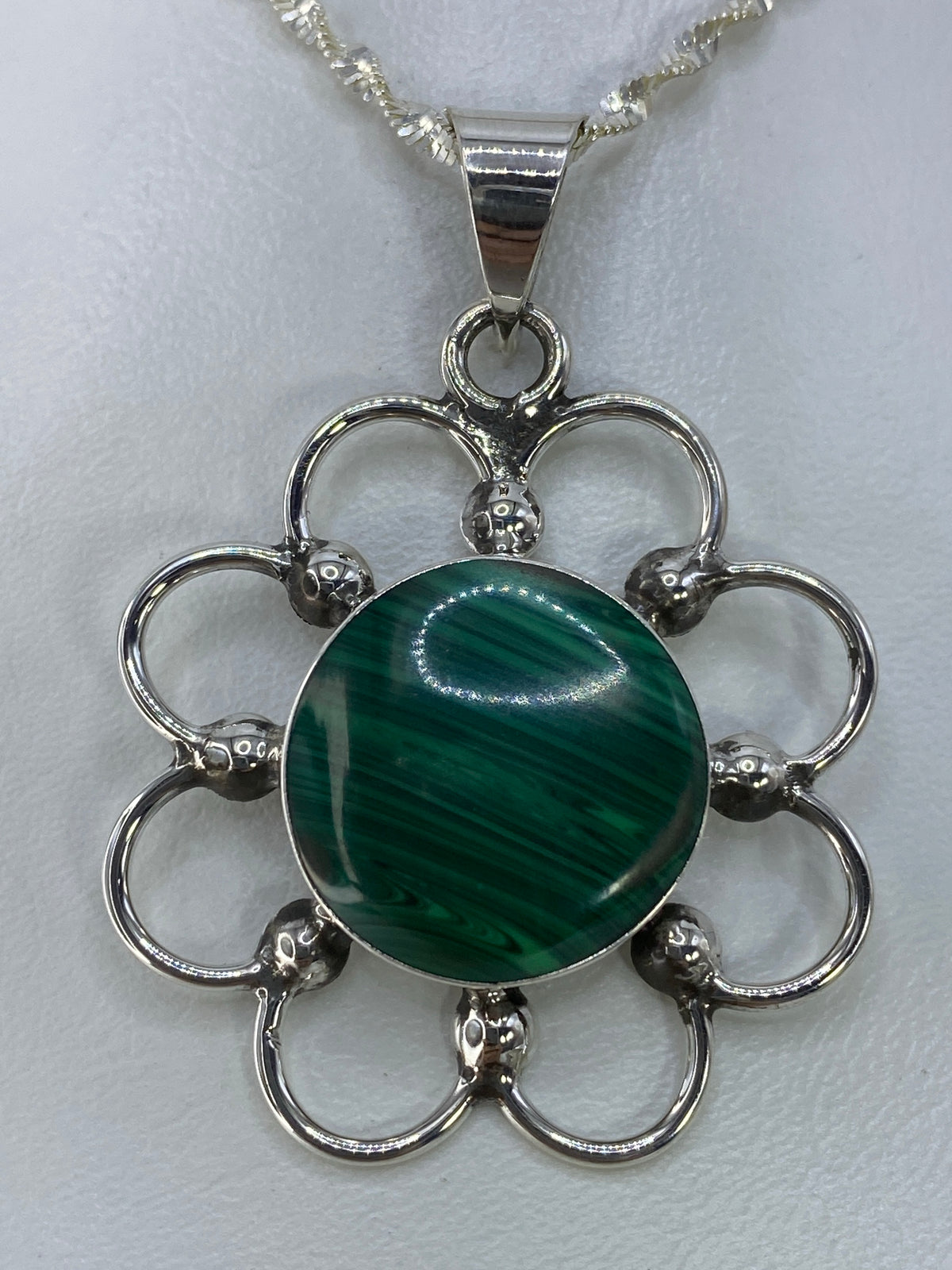 Dije de plata con piedra verde en forma de flor abierta, suspendido en cadena de plata