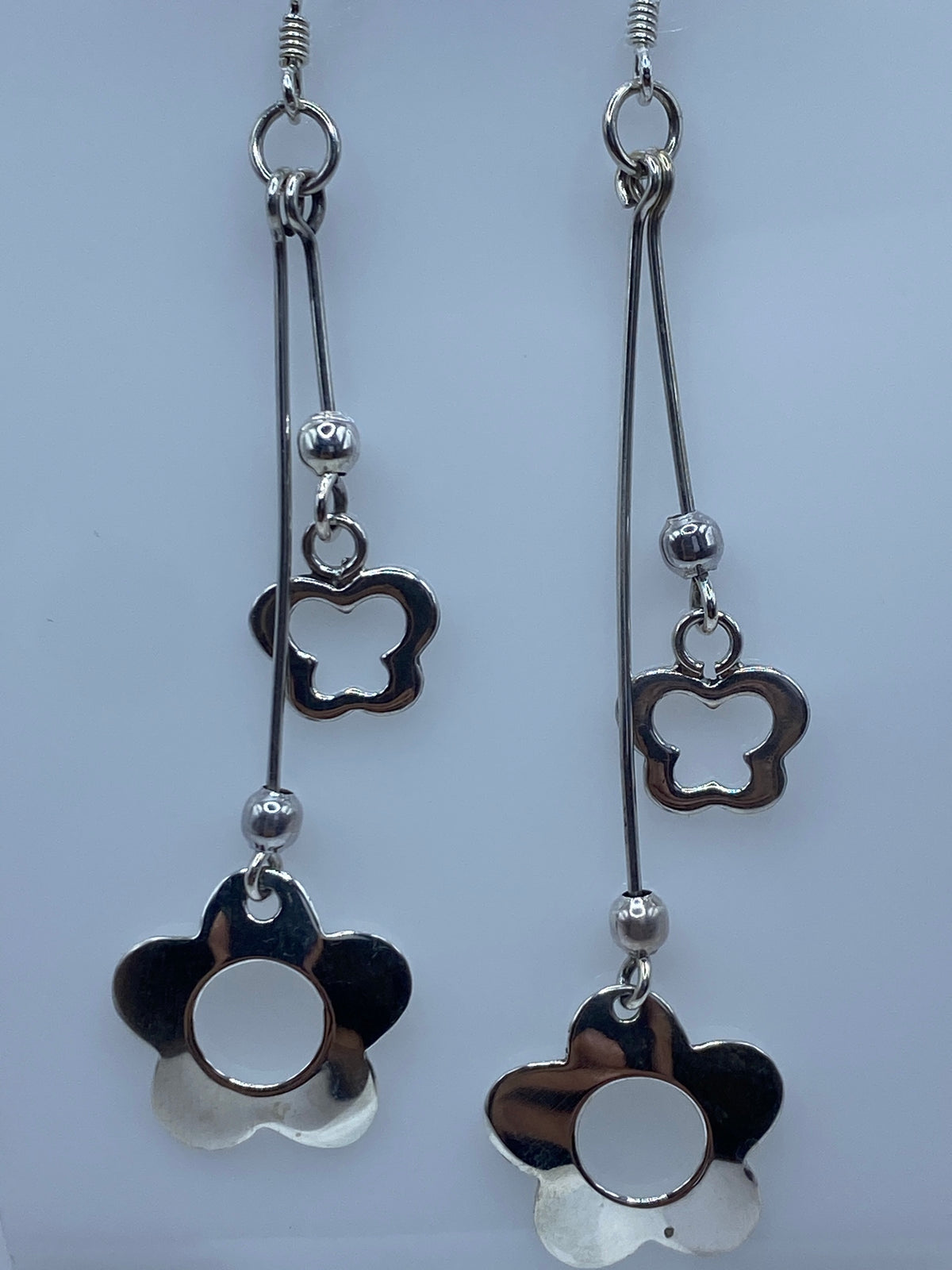 Aretes de plata sobre regla de centímetros marcando 8.4 cm de largo