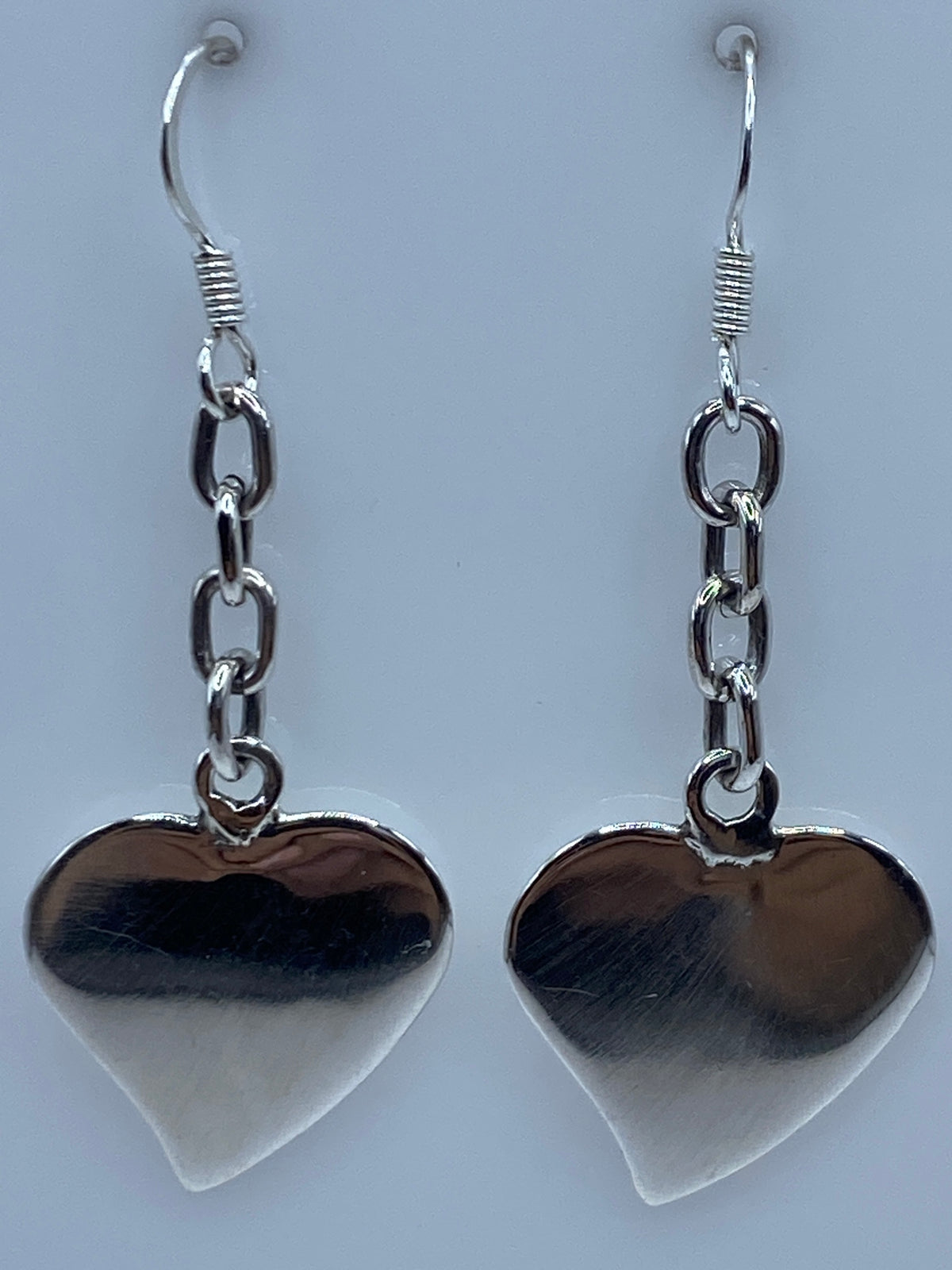 Par de aretes de plata 925 en forma de corazón, 5 cm, colgando sobre fondo gris