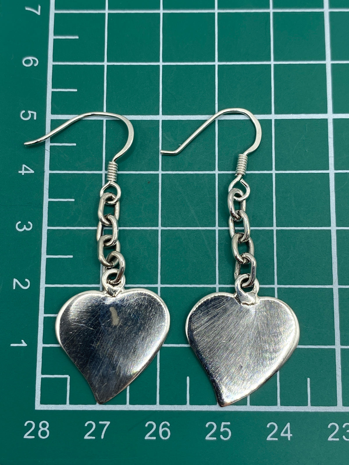Aretes de corazón en plata .925 con el Quinto grabado, vista frontal