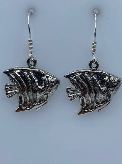 Los dos aretes juntos sobre fondo azul, mostrando el trabajo de repujado artesanal