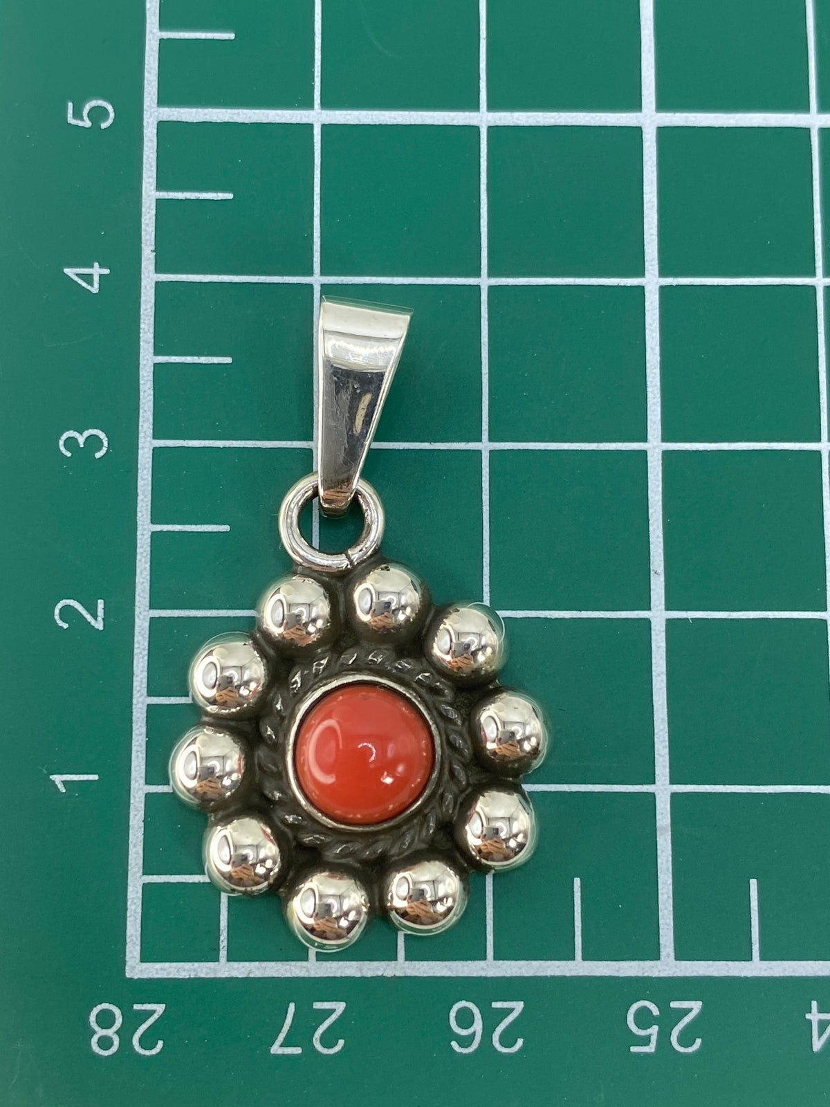Dije de plata con coral colgando de cadena de eslabones plateados