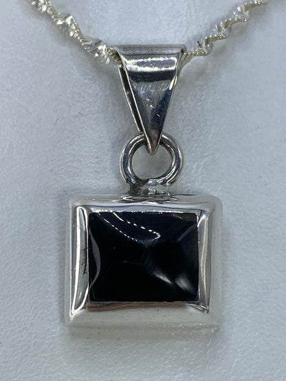 Detalle frontal del dije de ónix negro en marco de plata pulida