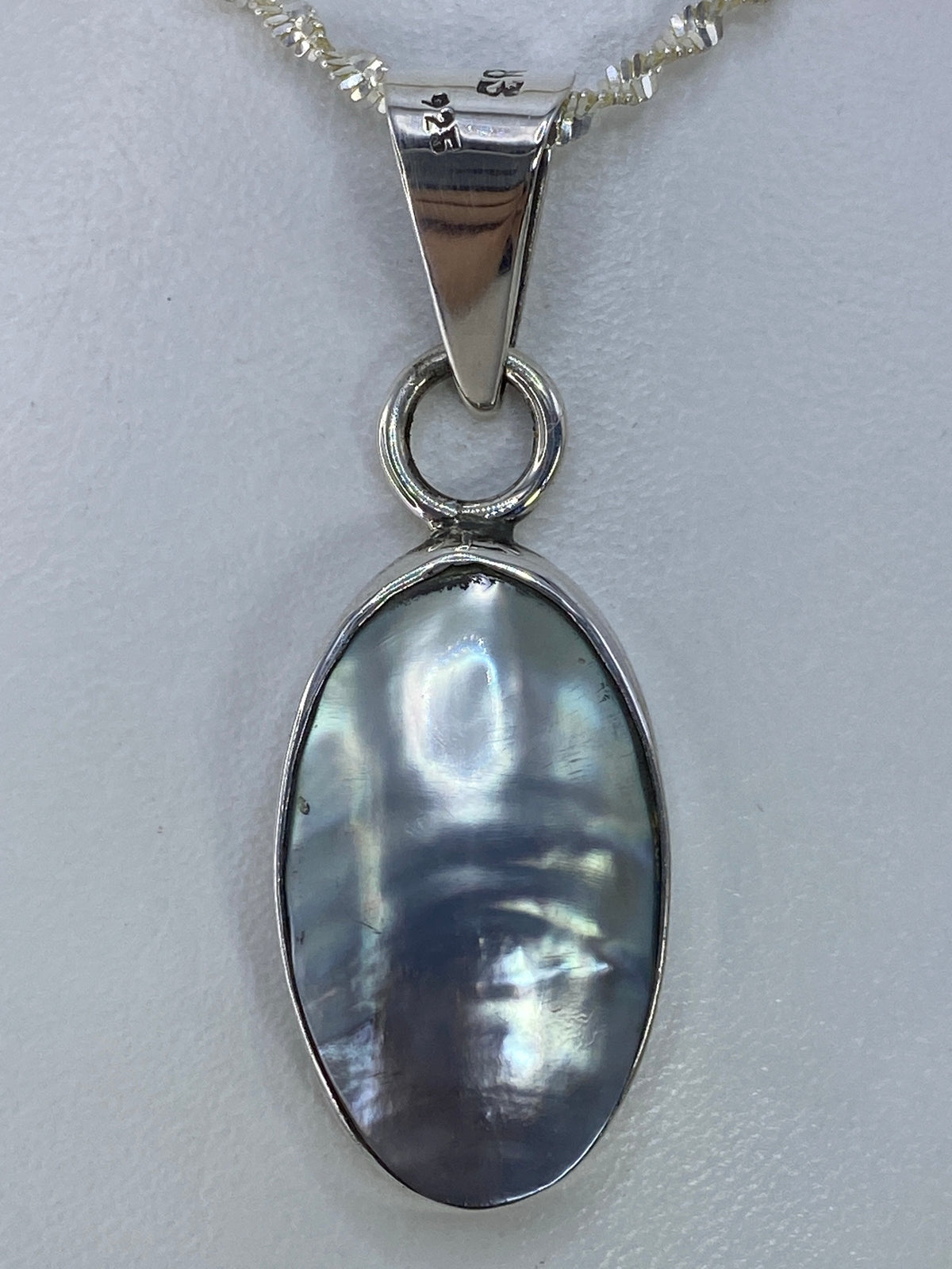 Dije de plata 925 con piedra engastada ovalada, color gris iridiscente, sobre cadena de eslabones