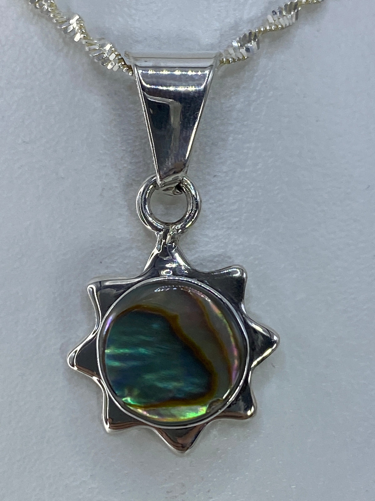 Dije de plata en forma de estrella de 8 puntas con piedra multicolor que refleja verdes, azules y amarillos