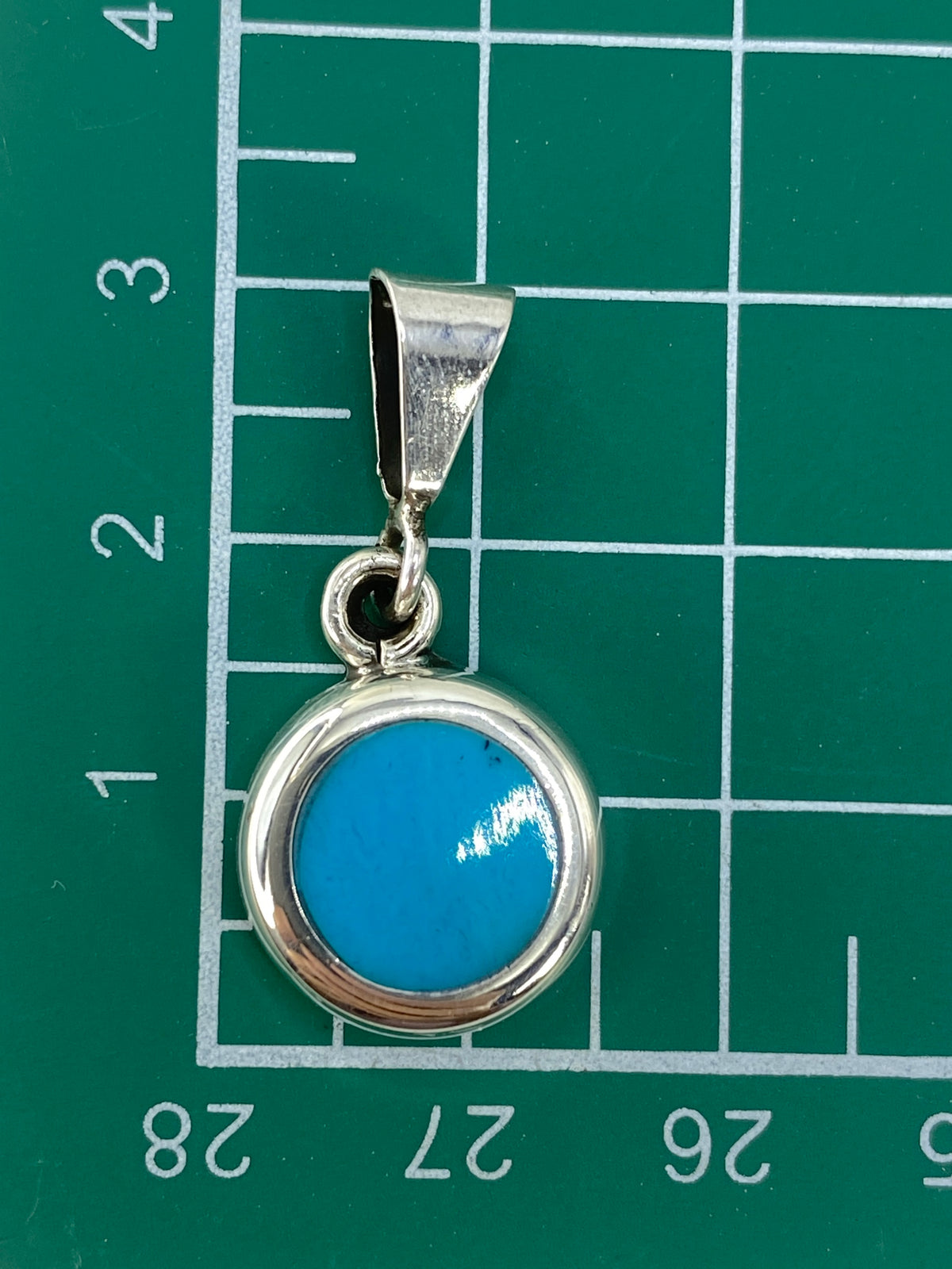 Dije de turquesa sobre escala mostrando 5.4 gramos de peso