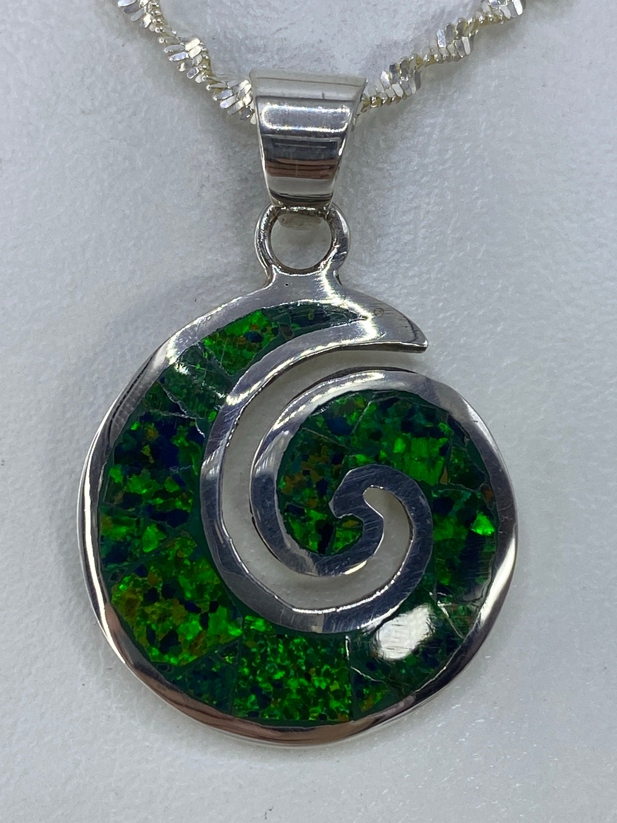 Dije de plata con ópalo de fuego verde en forma de espiral, vista frontal