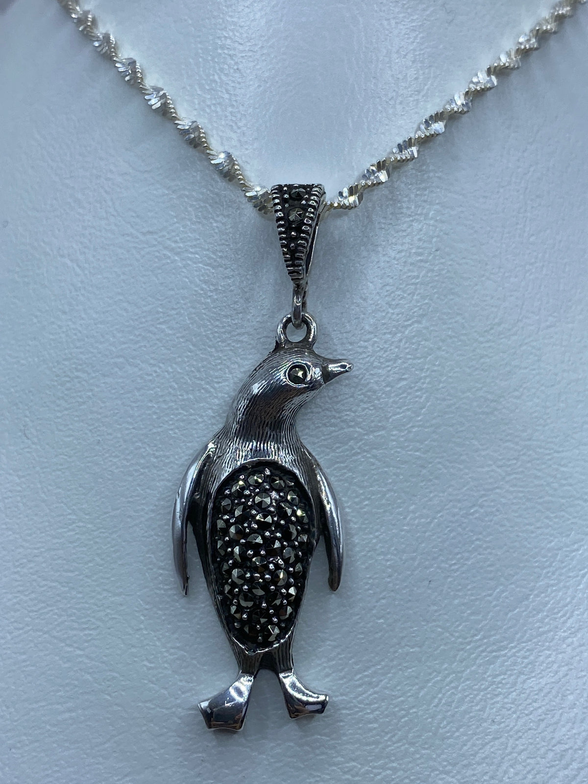 Dije de pingüino de plata 925 con marcasita incrustada, colgando de una cadena plateada