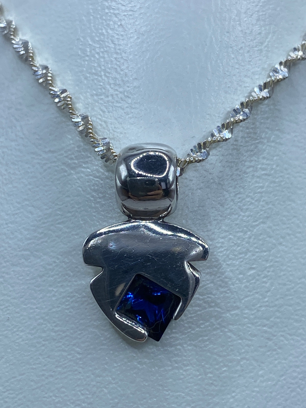 Detalle de la circonia azul reflejando la luz en el dije de plata