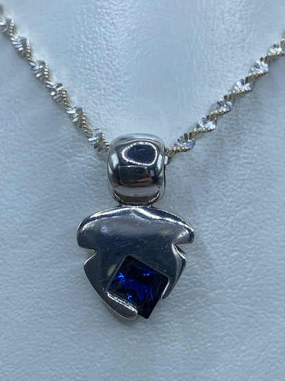 Detalle de la circonia azul reflejando la luz en el dije de plata