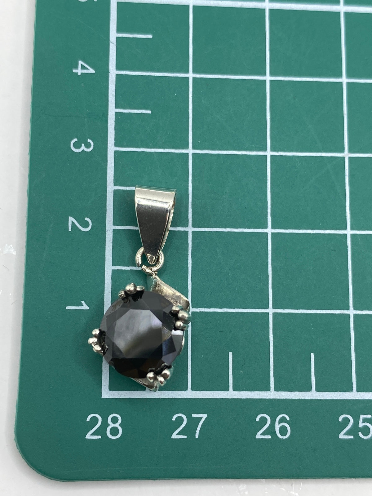 Dije sobre escala de medidas mostrando 2.5 cm de largo, con marca del Quinto 925