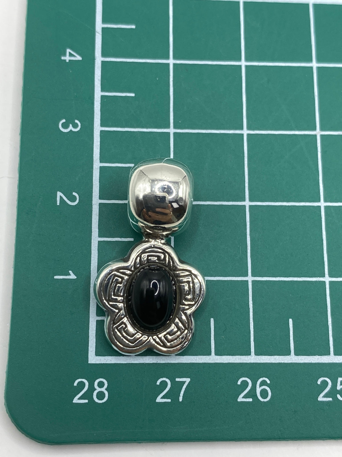 Dije de plata prehispánico sobre fondo blanco, tamaño real (2.4 × 1.4 cm)