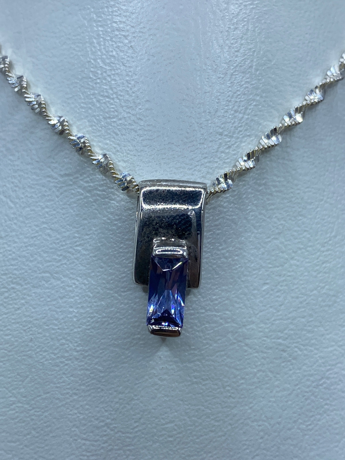 Dije de plata 925 con circonia morada engastada, colgando de cadena plateada