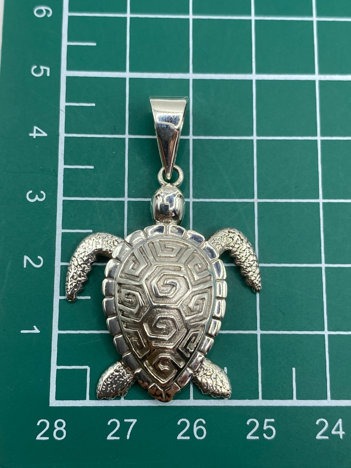 Dije tortuga en escala con regla, mostrando tamaño real de 4.3 cm de largo