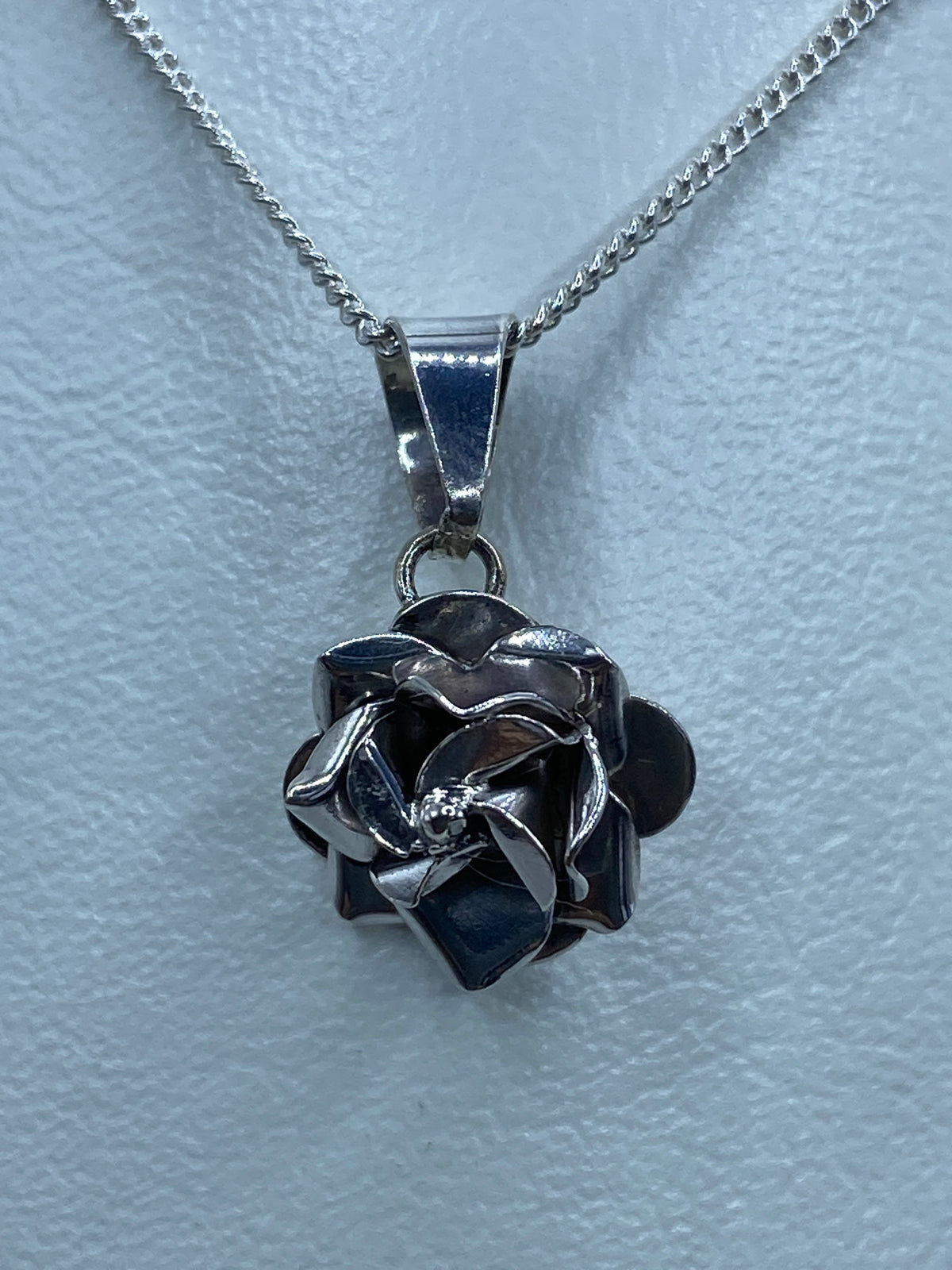 Dije flor sobre cinta de medición mostrando su tamaño de 1.9 cm