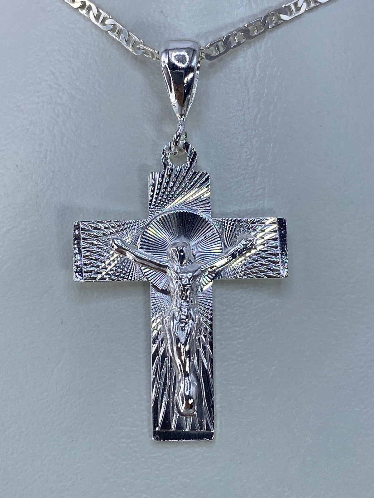 Detalle frontal del Cristo repujado en el dije de cruz