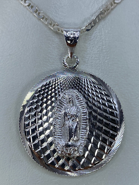 Primer plano del rostro de la Virgen de Guadalupe en el dije, mostrando el detalle del repujado a mano