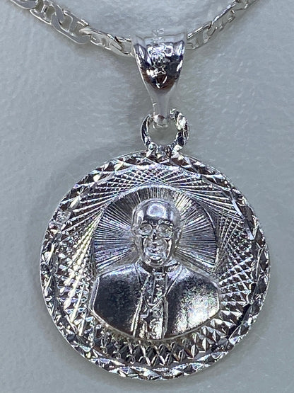 Dije de plata repujado con retrato en relieve y halo radiante, vista frontal