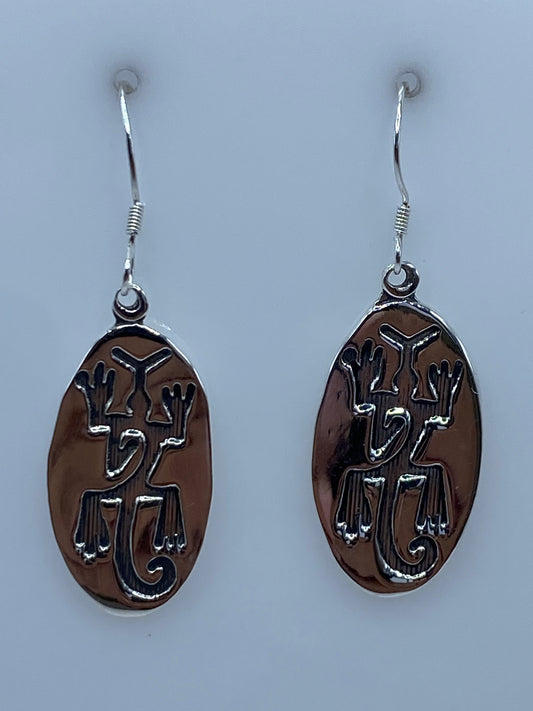 Aretes de plata repujados con motivos prehispánicos colgando del gancho