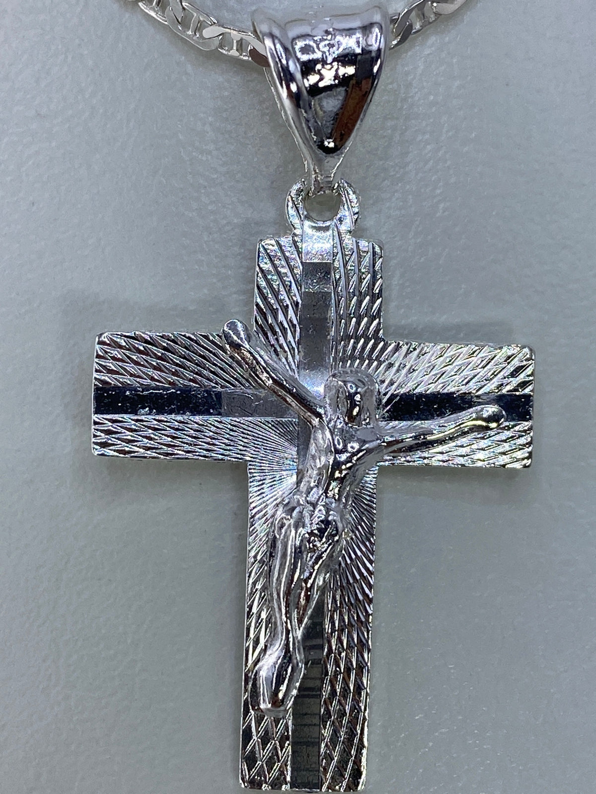 Detalle lateral del dije cruz de 4 cm con acabado de repujado