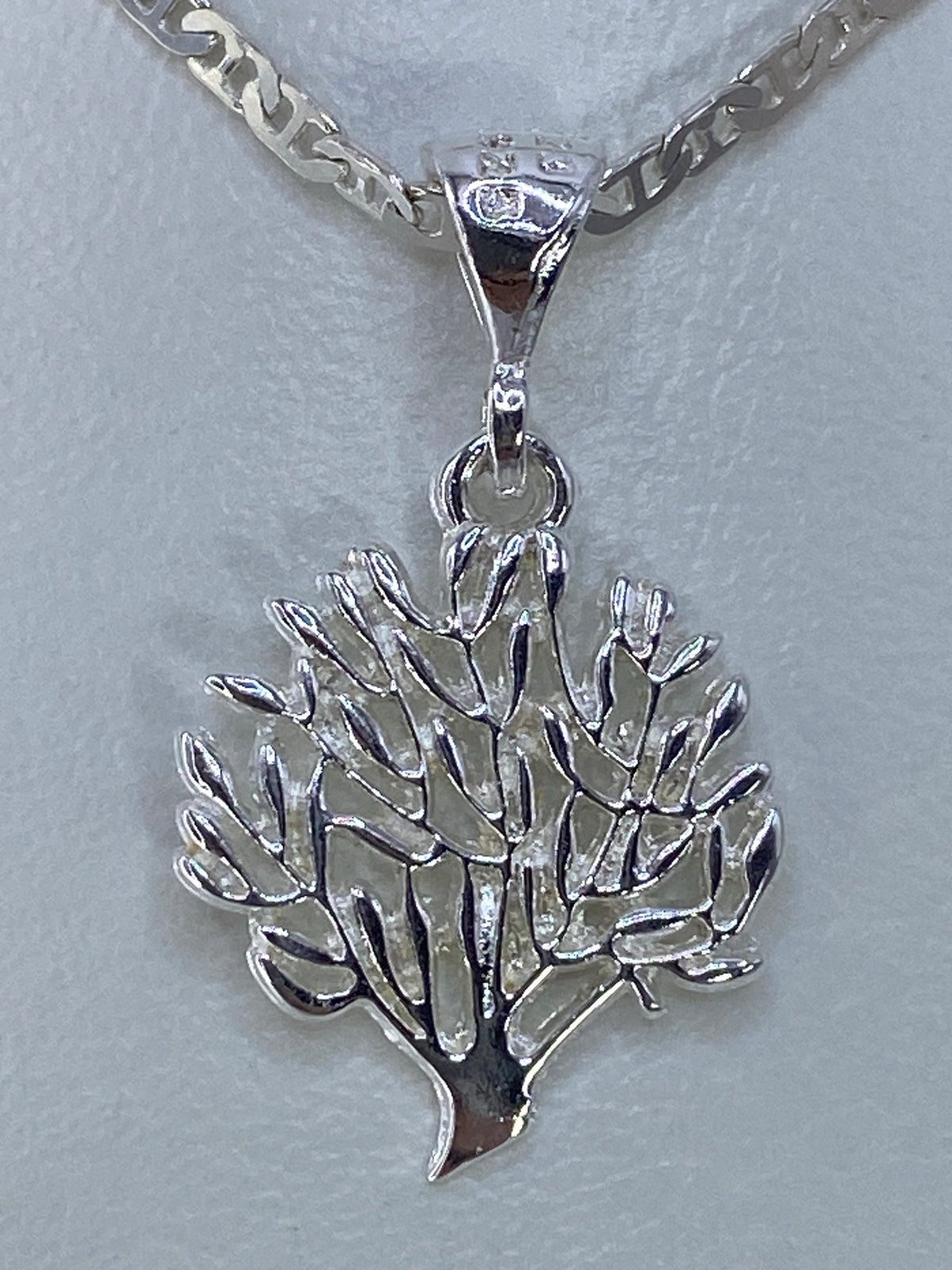 Dije de plata 925 con diseño floral calado, colgando de una cadena plateada