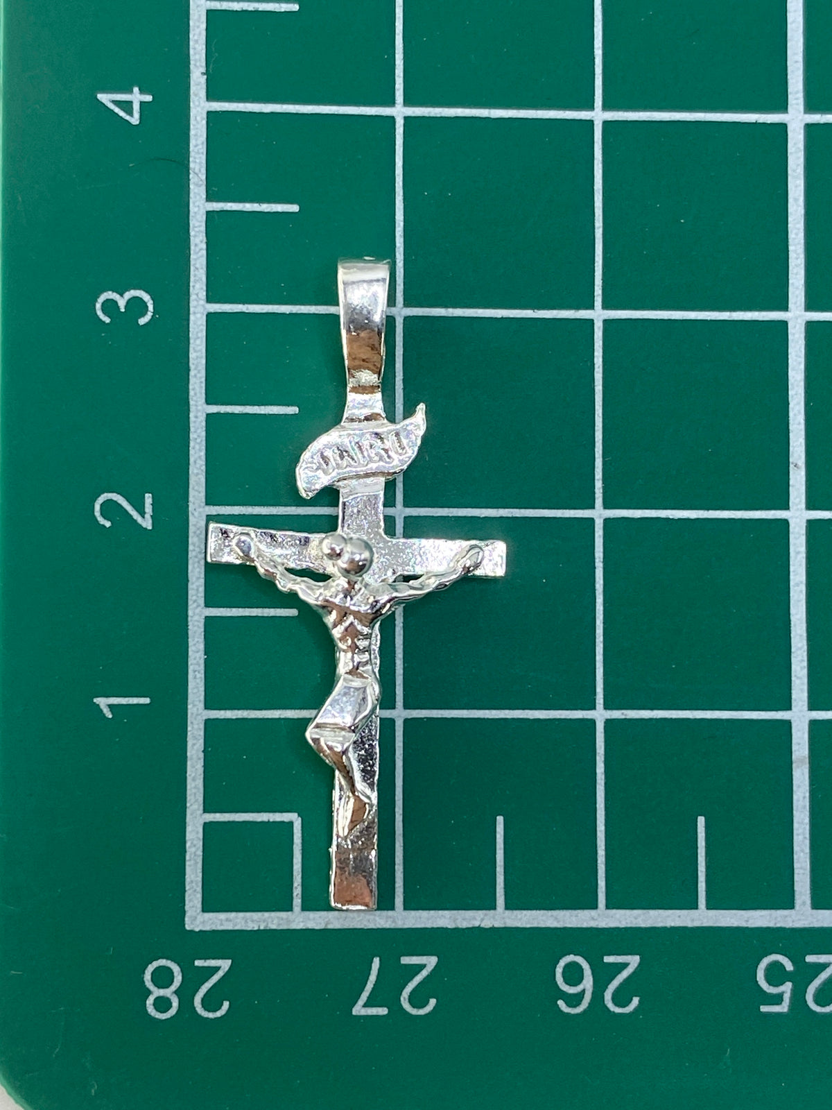Crucifijo de plata sobre fondo blanco mostrando la marca del Quinto 925