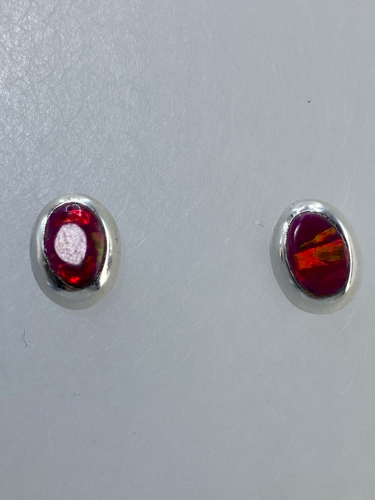 Aretes con poste y tuerca en plata, ópalo multicolor bajo luz natural
