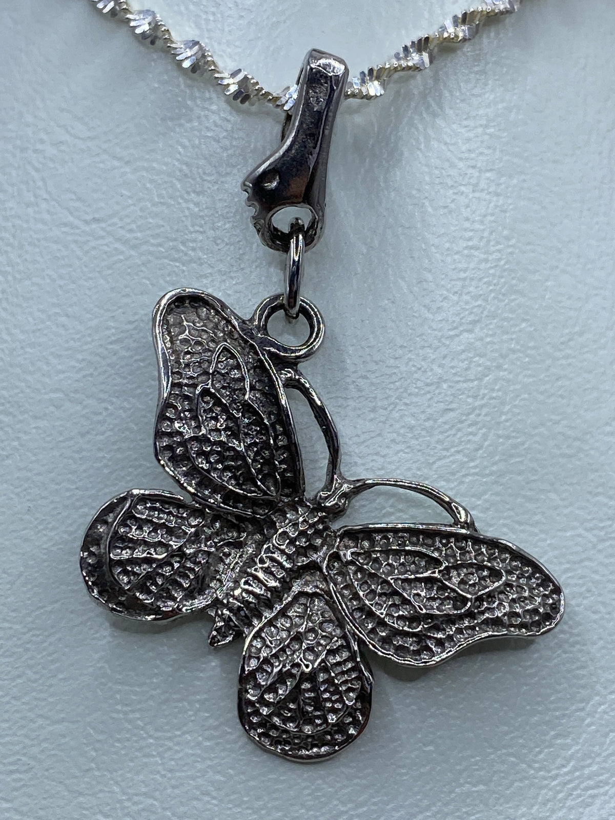 Dije de mariposa sobre fondo blanco con las alas extendidas