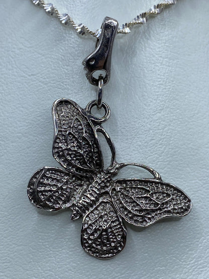 Dije de mariposa sobre fondo blanco con las alas extendidas