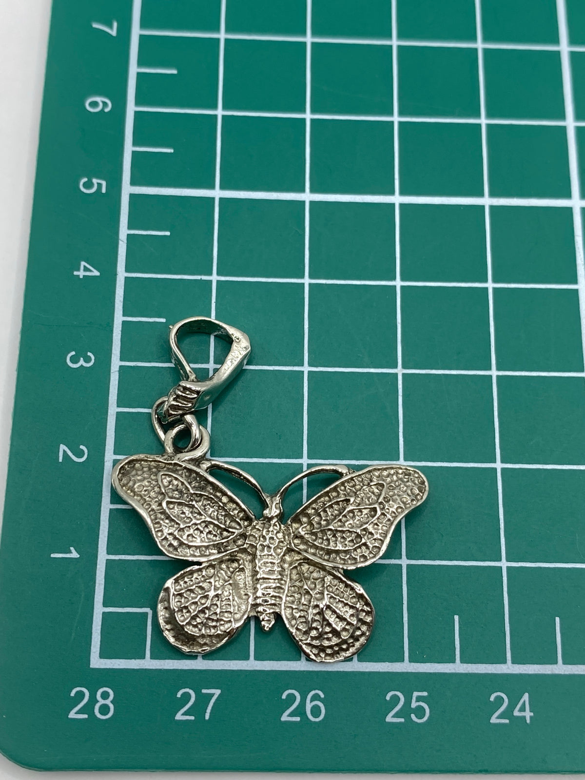 Mariposa de plata 925 en la palma de la mano mostrando el tamaño real de 4.3 cm