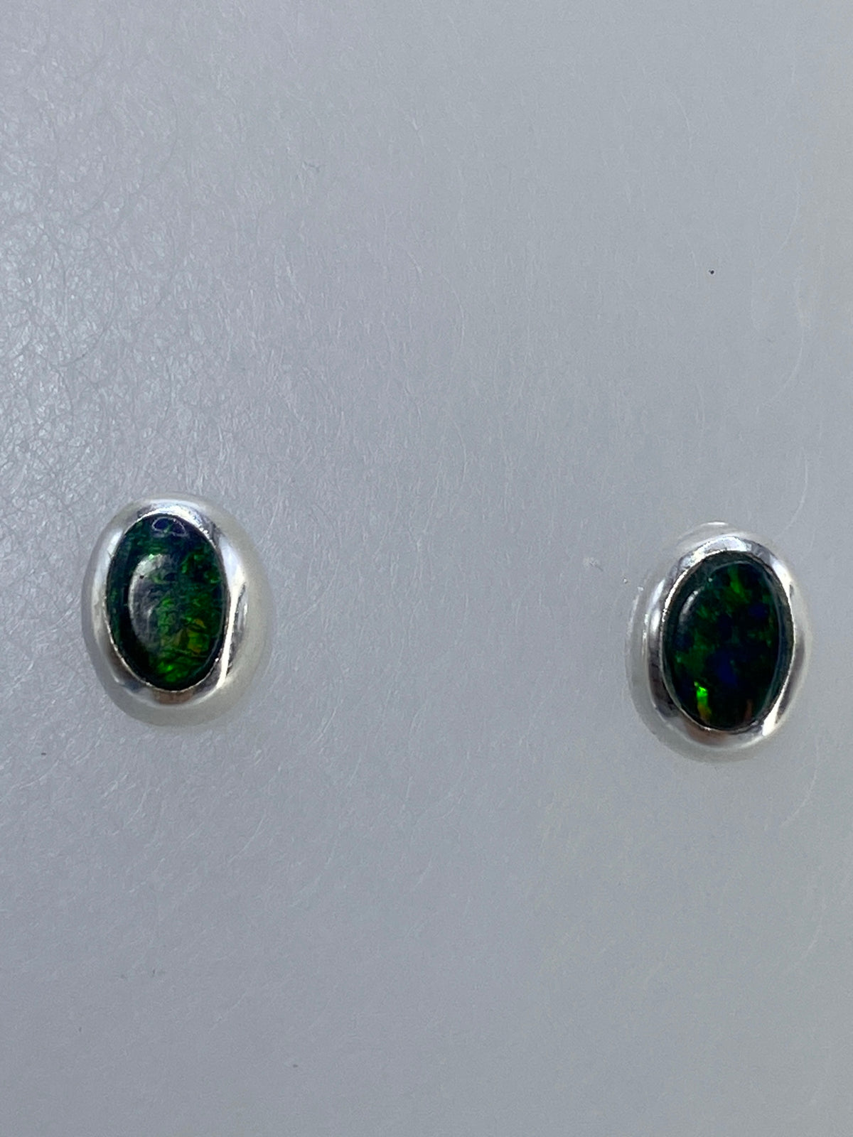 Par de aretes de plata 925 con ópalo de fuego verde engastado a mano, visto sobre fondo blanco