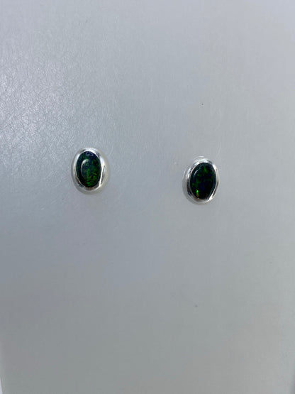 Detalle frontal de los aretes mostrando el brillo verde del ópalo de fuego