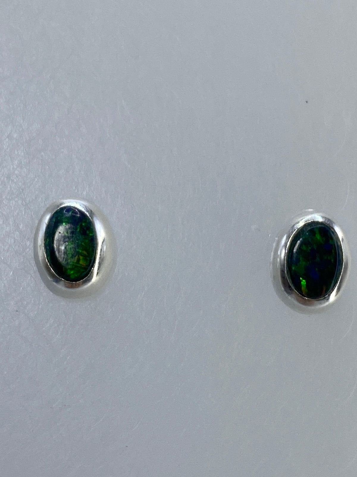 Aretes de plata junto a regla de centímetros para referencia de tamaño