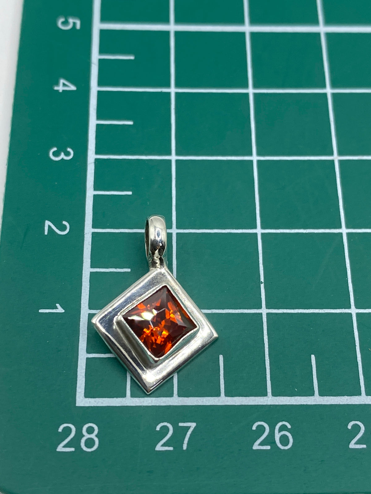 Dije cuadrado de plata 925 junto a escala de centímetros midiendo 2 × 1.5 cm