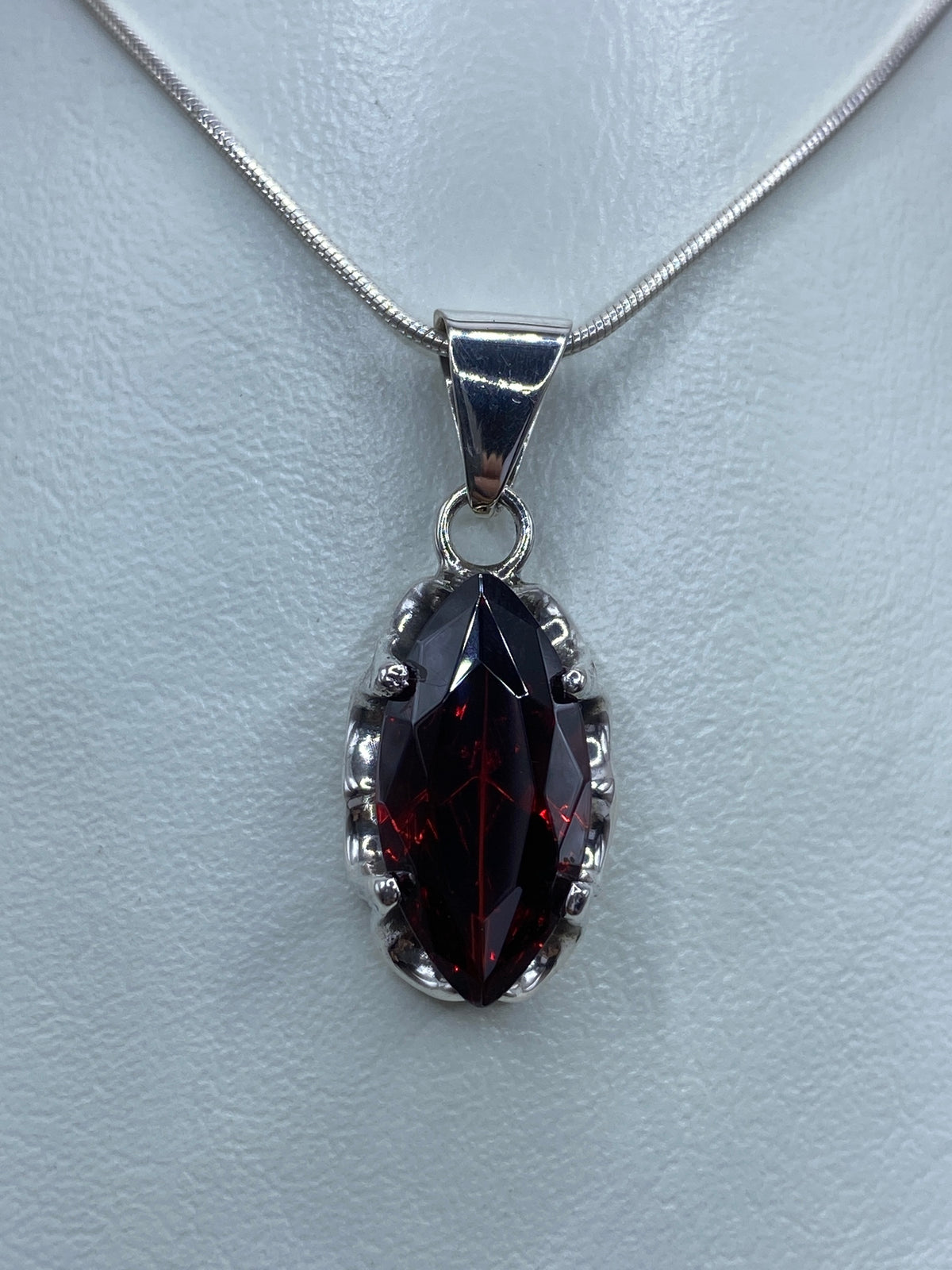 Dije de plata con circonia roja engastada, colgando de cadena de plata, vista frontal