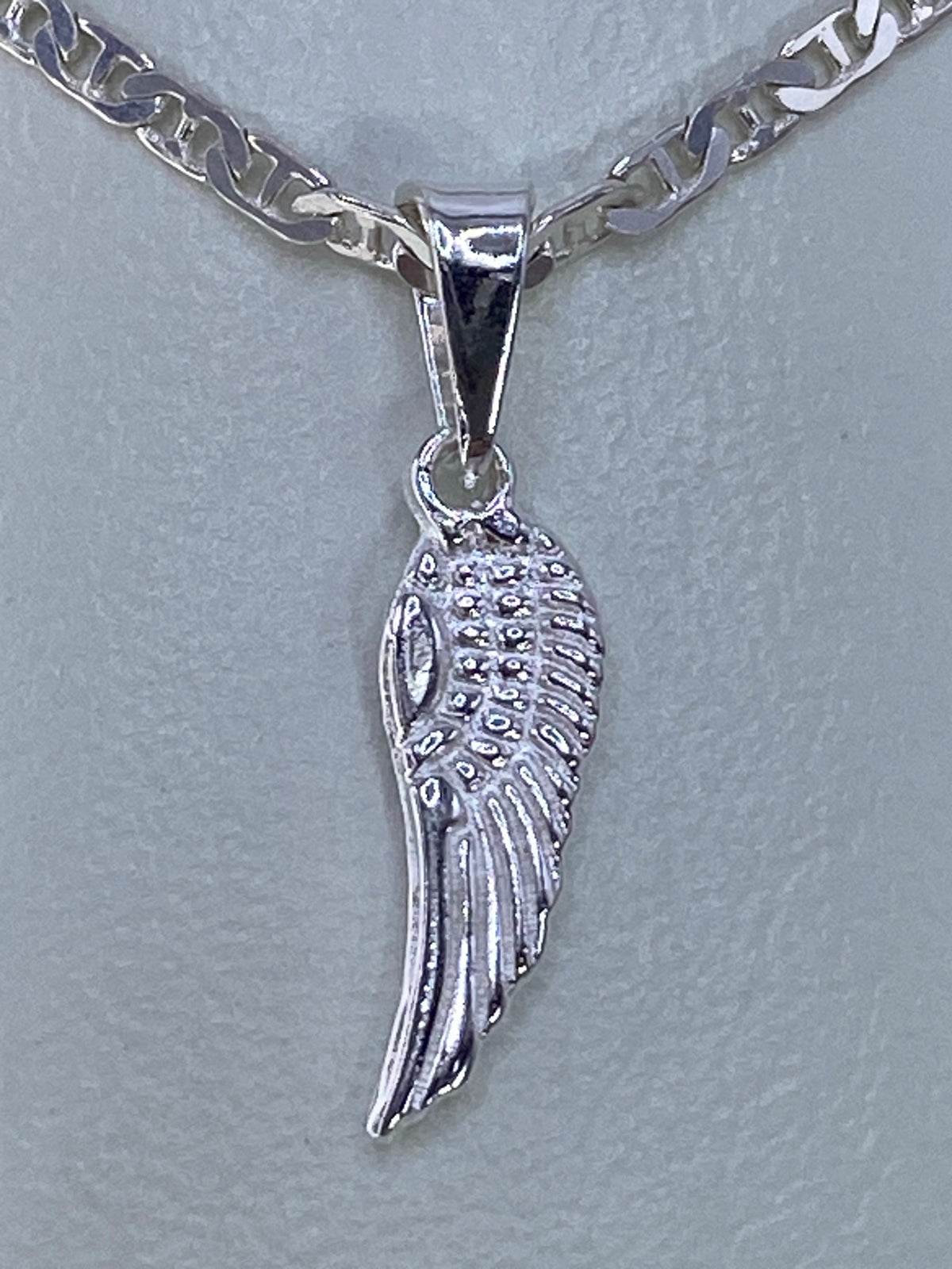 Dije ala de ángel en plata 925 repujada a mano, vista frontal con cadena plateada