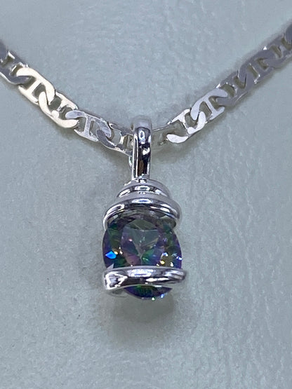 Detalle del dije de plata mostrando la circonia con destellos en azul, verde, amarillo y púrpura